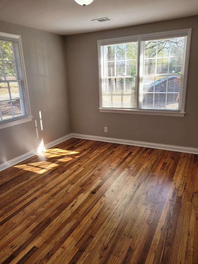 spare room featuring plenty of natural light and dark hardwood / wood-style flooring