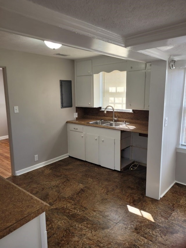 kitchen featuring white cabinets, a textured ceiling, tasteful backsplash, and sink