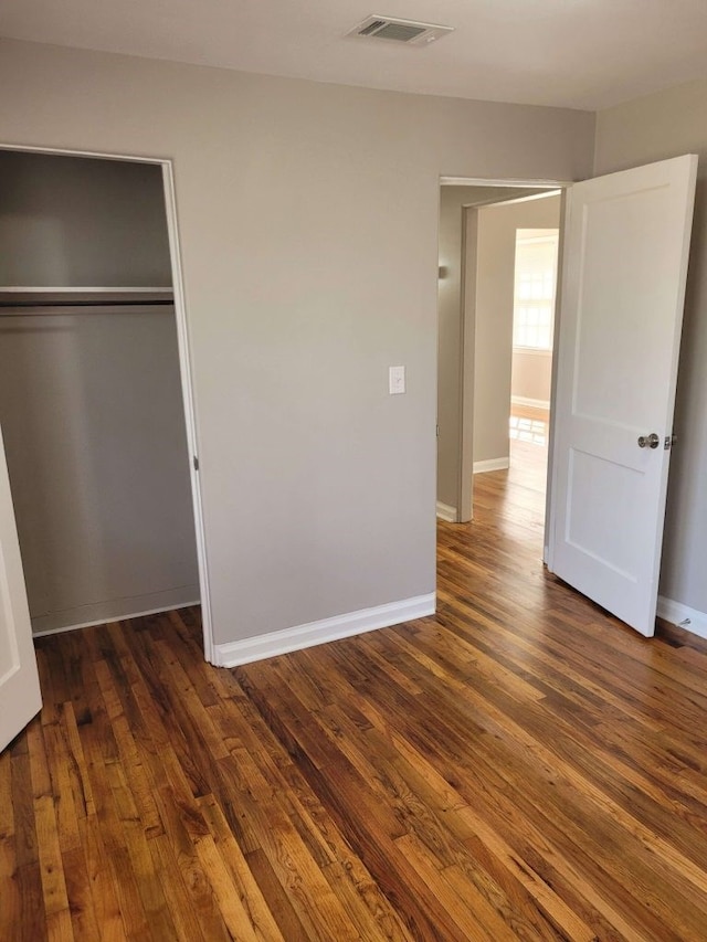 unfurnished bedroom featuring a closet and dark hardwood / wood-style floors