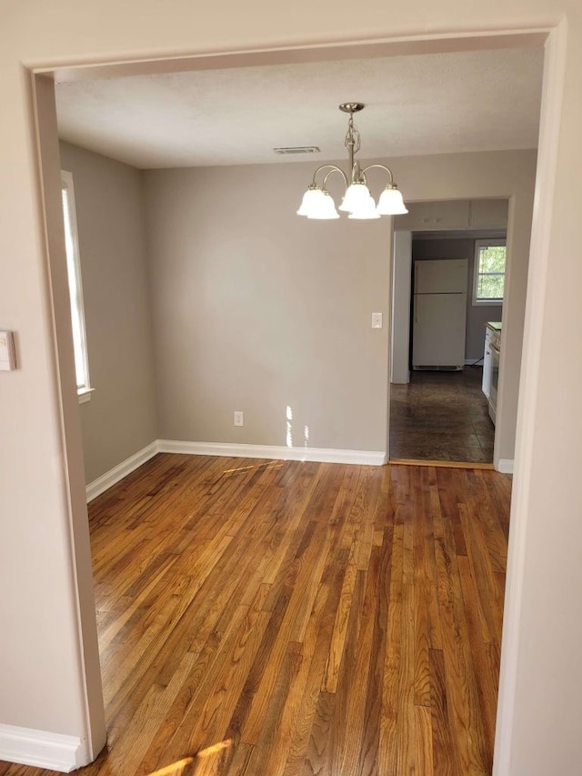 unfurnished dining area featuring a chandelier and hardwood / wood-style flooring