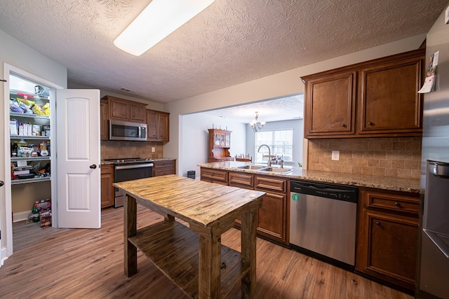 37 Oakwood Dr, Phenix City, AL 36870 - kitchen featuring appliances with stainless steel finishes, light wood-style floors, a peninsula, backsplash, and a textured ceiling