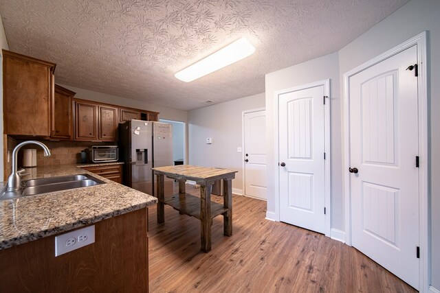 37 Oakwood Dr, Phenix City, AL 36870 - kitchen with stainless steel fridge with ice dispenser, light wood finished floors, decorative backsplash, and a textured ceiling
