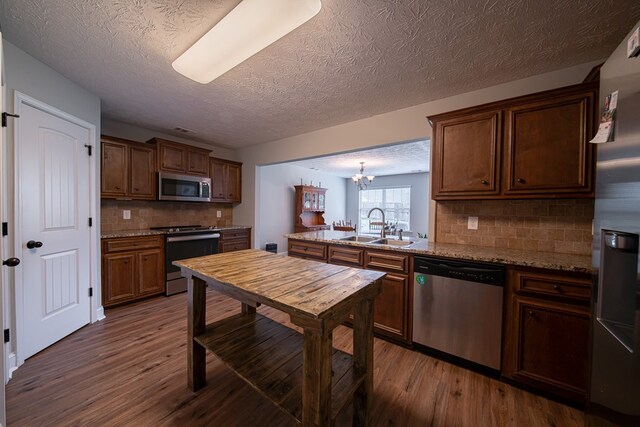 37 Oakwood Dr, Phenix City, AL 36870 - kitchen with appliances with stainless steel finishes, dark wood-style floors, tasteful backsplash, a textured ceiling, and a peninsula
