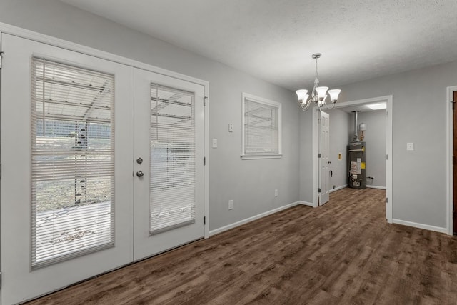 unfurnished dining area featuring a textured ceiling, dark hardwood / wood-style flooring, french doors, a notable chandelier, and gas water heater