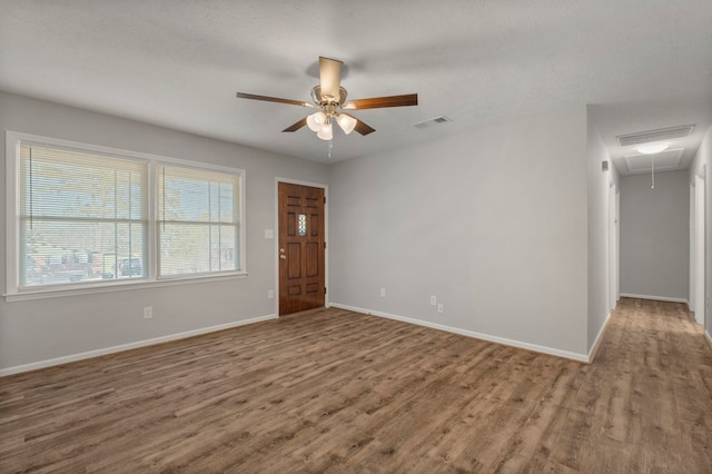 empty room with ceiling fan, wood-type flooring, and a textured ceiling