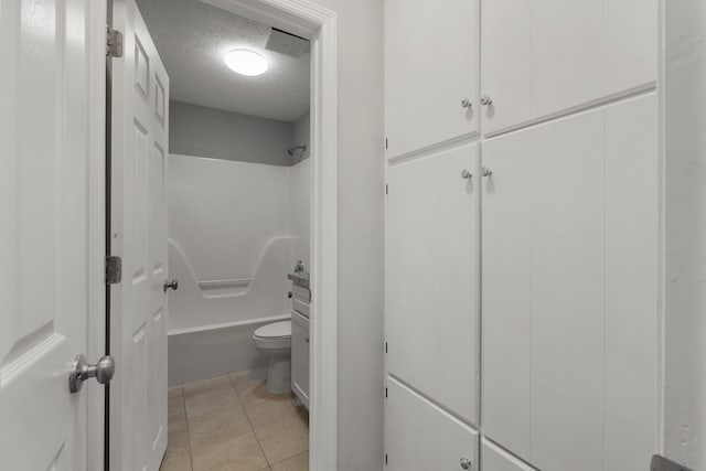 bathroom featuring a textured ceiling, toilet, and tile patterned flooring