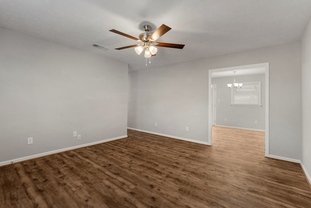 empty room with dark hardwood / wood-style flooring, ceiling fan with notable chandelier, and a textured ceiling