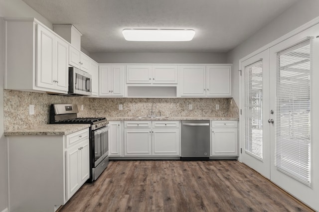 kitchen featuring a textured ceiling, white cabinetry, stainless steel appliances, decorative backsplash, and sink