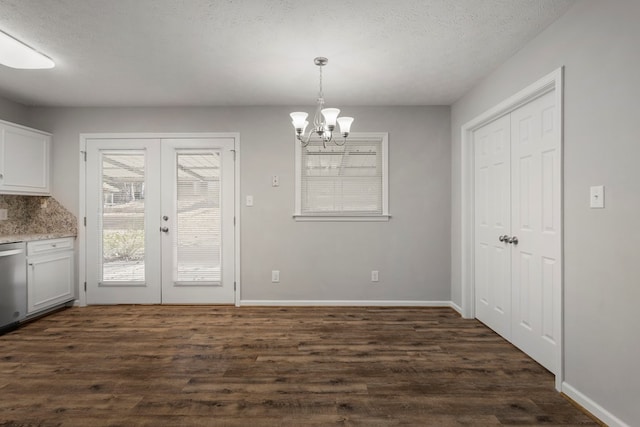 unfurnished dining area with french doors, dark hardwood / wood-style flooring, an inviting chandelier, and a textured ceiling