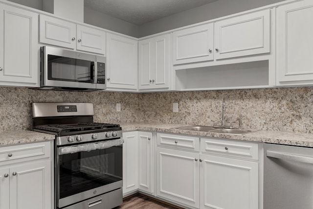 kitchen featuring a textured ceiling, appliances with stainless steel finishes, white cabinets, and sink