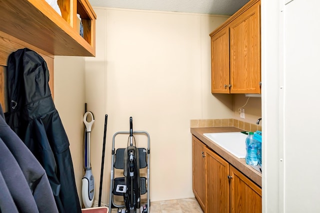 clothes washing area featuring light tile patterned floors and sink