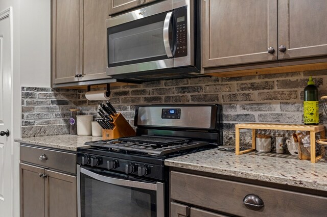 7546 Mockernut Way, Midland, GA 31820 - kitchen featuring appliances with stainless steel finishes, backsplash, and light stone countertops