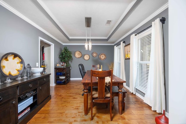 dining room featuring visible vents, crown molding, light wood finished floors, a chandelier, and a tray ceiling