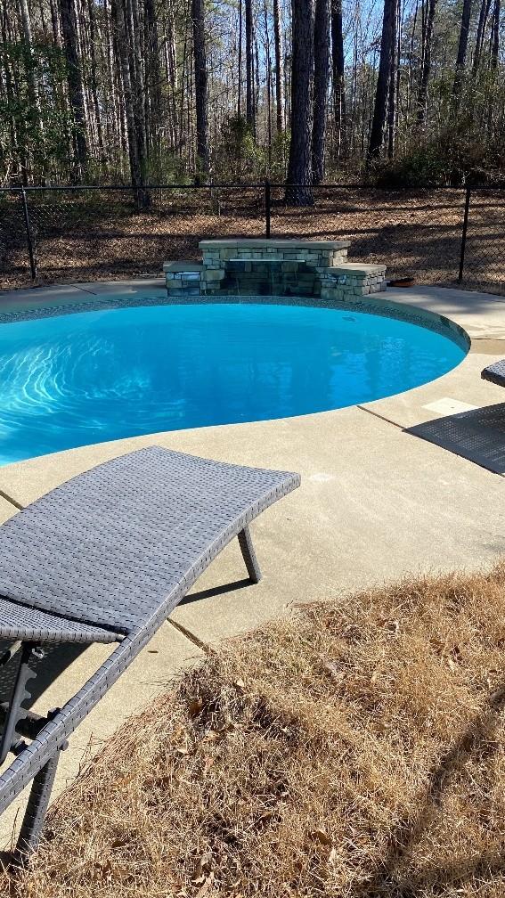 outdoor pool featuring fence and a patio area