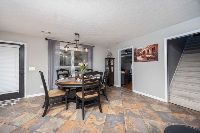 dining area featuring a textured ceiling, baseboards, visible vents, stairway, and stone tile flooring