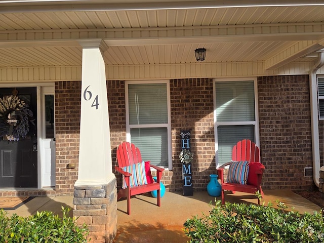 property entrance with a porch and brick siding