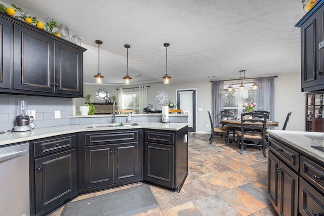kitchen with a sink, a textured ceiling, a peninsula, decorative light fixtures, and stainless steel dishwasher