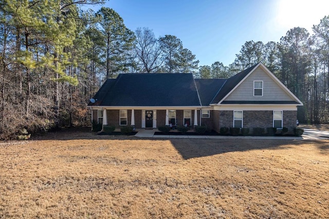 view of front of house with brick siding, covered porch, and a front yard