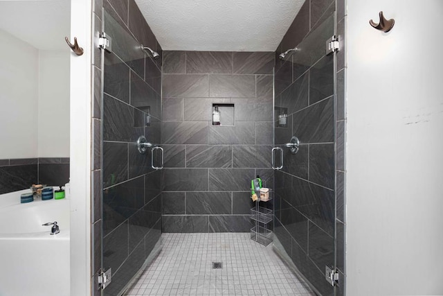 full bathroom featuring a textured ceiling, a bath, and a shower stall