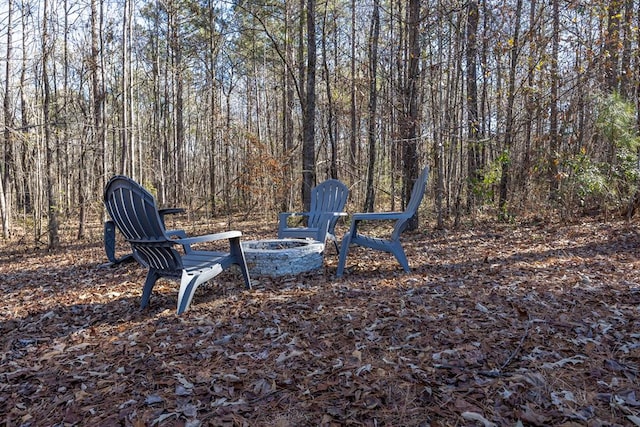 view of yard featuring an outdoor fire pit and a forest view