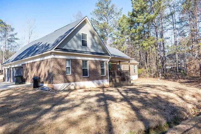 view of home's exterior with brick siding, a garage, and covered porch