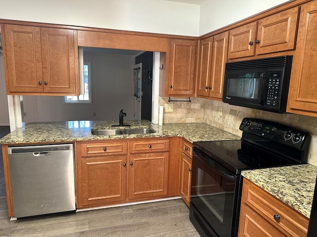 kitchen featuring light stone countertops, tasteful backsplash, sink, black appliances, and hardwood / wood-style flooring