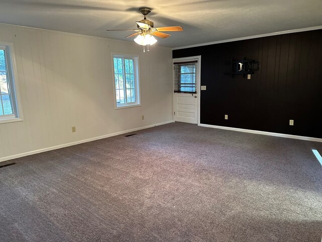 spare room with carpet floors, ceiling fan, crown molding, and wood walls