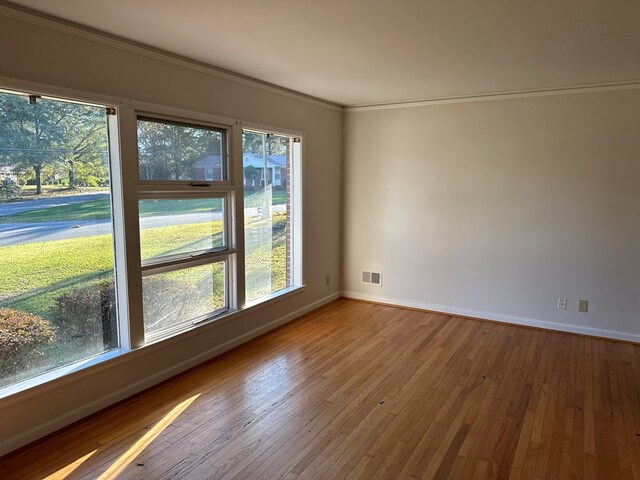 empty room with light wood-type flooring and crown molding