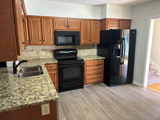 kitchen with black appliances, decorative backsplash, light hardwood / wood-style floors, and sink