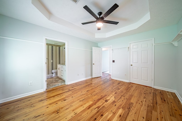 177 Wright Rd, Pine Mountain, GA 31822 - unfurnished bedroom featuring light wood-style flooring, a tray ceiling, ensuite bath, and a ceiling fan