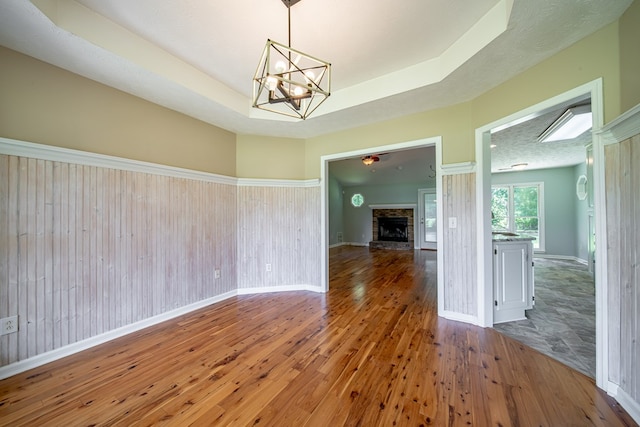 177 Wright Rd, Pine Mountain, GA 31822 - unfurnished dining area featuring wood-type flooring, a chandelier, a fireplace, and a tray ceiling