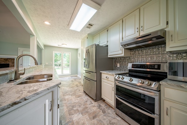 177 Wright Rd, Pine Mountain, GA 31822 - kitchen with appliances with stainless steel finishes, under cabinet range hood, a textured ceiling, tasteful backsplash, and light stone counters