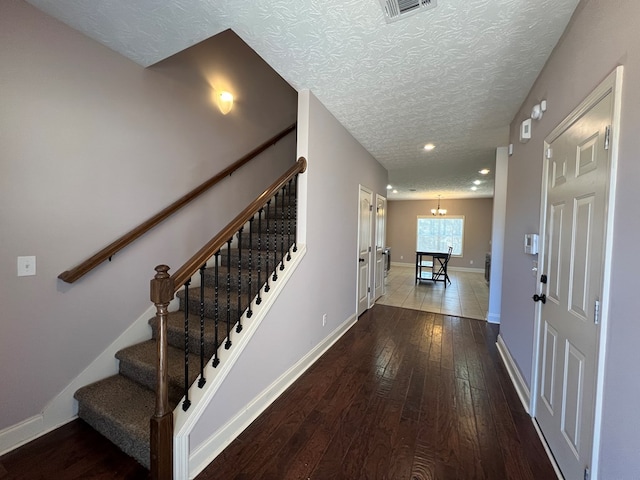 entryway with hardwood / wood-style floors, a textured ceiling, and an inviting chandelier