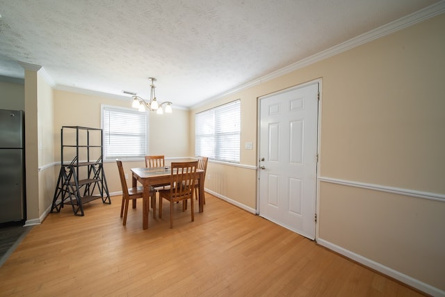 dining area featuring ornamental molding, a chandelier, light hardwood / wood-style flooring, and a textured ceiling