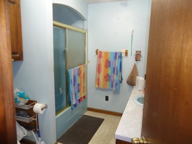 full bathroom with vanity, baseboards, and shower / bath combination with glass door