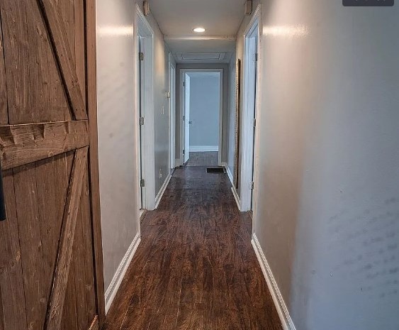 hallway with dark wood-style flooring and baseboards