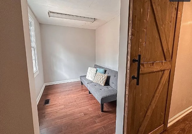 sitting room with baseboards, visible vents, and wood finished floors