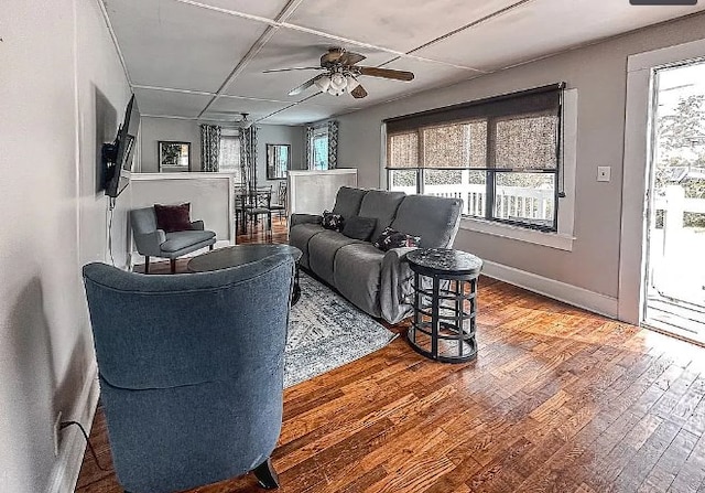 living area with a ceiling fan, baseboards, and wood finished floors