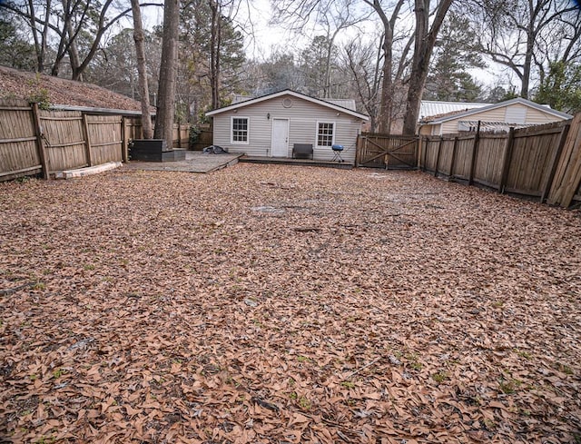 back of property with a fenced backyard and a gate