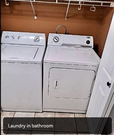 washroom with laundry area, light tile patterned floors, and washing machine and clothes dryer