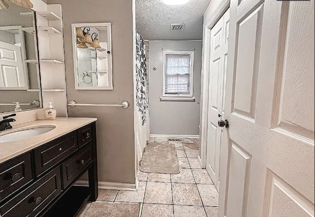 full bathroom featuring a textured ceiling, tile patterned flooring, vanity, visible vents, and baseboards