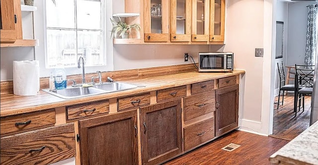 kitchen featuring dark wood-style floors, stainless steel microwave, light countertops, and a sink