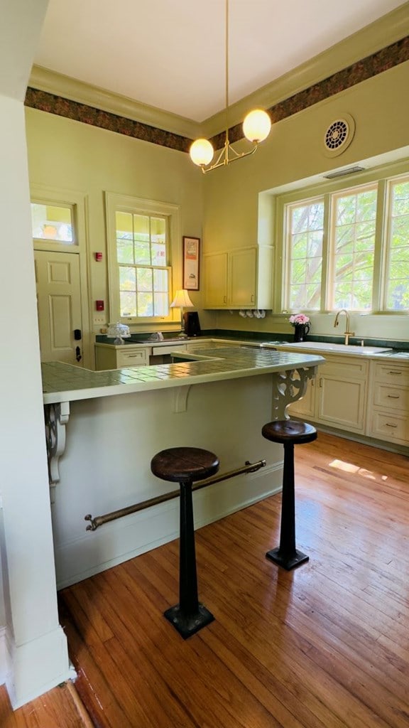 201 7th St, Columbus, GA 31901 - kitchen featuring a kitchen breakfast bar, light wood-style flooring, decorative light fixtures, and white cabinets
