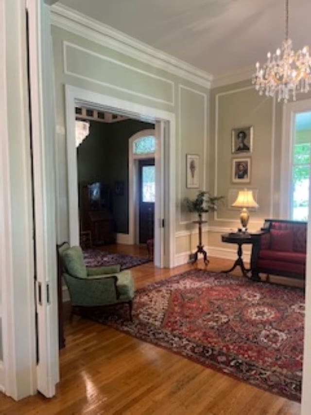 201 7th St, Columbus, GA 31901 - living area featuring ornamental molding, a chandelier, wood finished floors, and a decorative wall