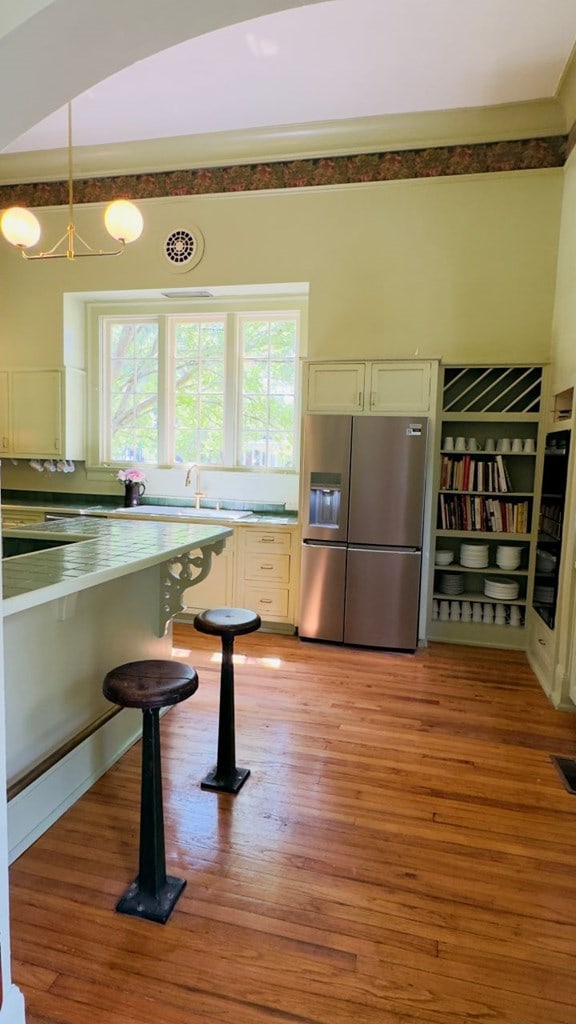 201 7th St, Columbus, GA 31901 - kitchen featuring stainless steel fridge with ice dispenser, light wood-style flooring, white cabinetry, and a chandelier