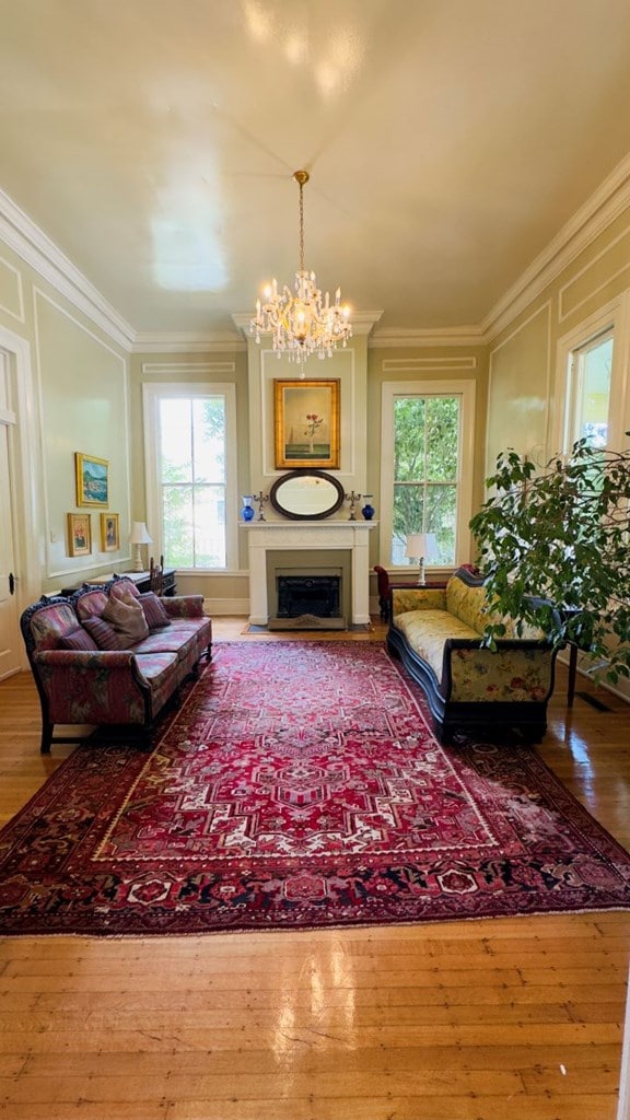201 7th St, Columbus, GA 31901 - living area with a decorative wall, a chandelier, wood finished floors, crown molding, and a fireplace with flush hearth