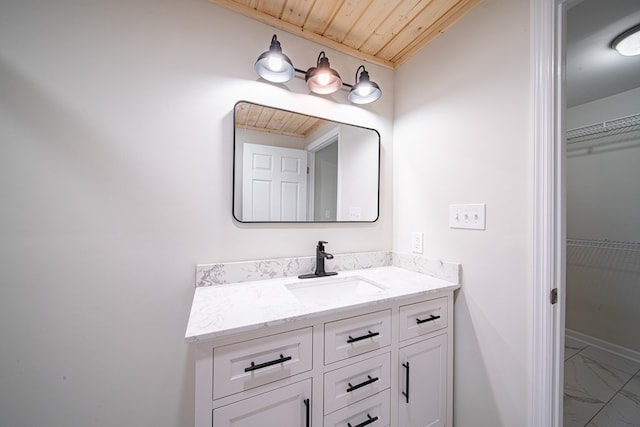 bathroom featuring marble finish floor, vanity, wooden ceiling, baseboards, and a spacious closet