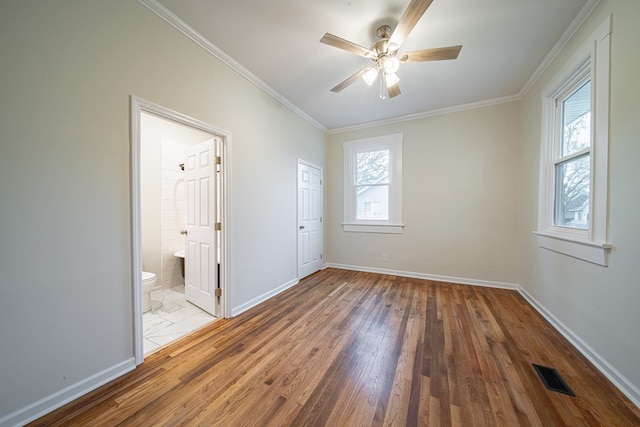 unfurnished bedroom featuring crown molding, hardwood / wood-style flooring, baseboards, and visible vents