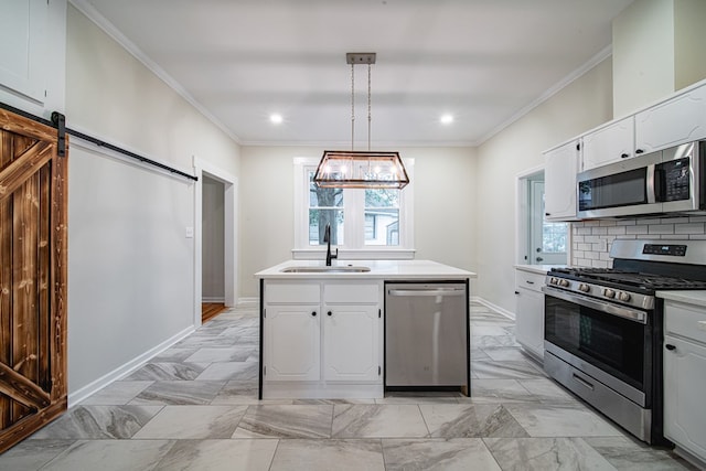 kitchen with ornamental molding, a sink, backsplash, a barn door, and appliances with stainless steel finishes