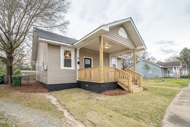 bungalow-style home featuring a front yard, fence, a porch, a shingled roof, and crawl space